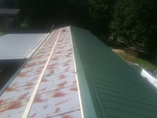 Old rusted panels beside newly installed green metal roofing — Wind Damage Roof Repair by Roofing Brothers in Indio