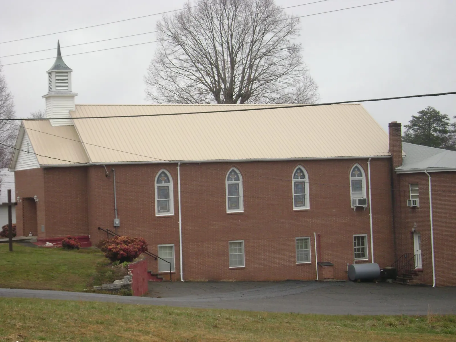 New tan metal roof on a brick church with a white steeple in Indio
