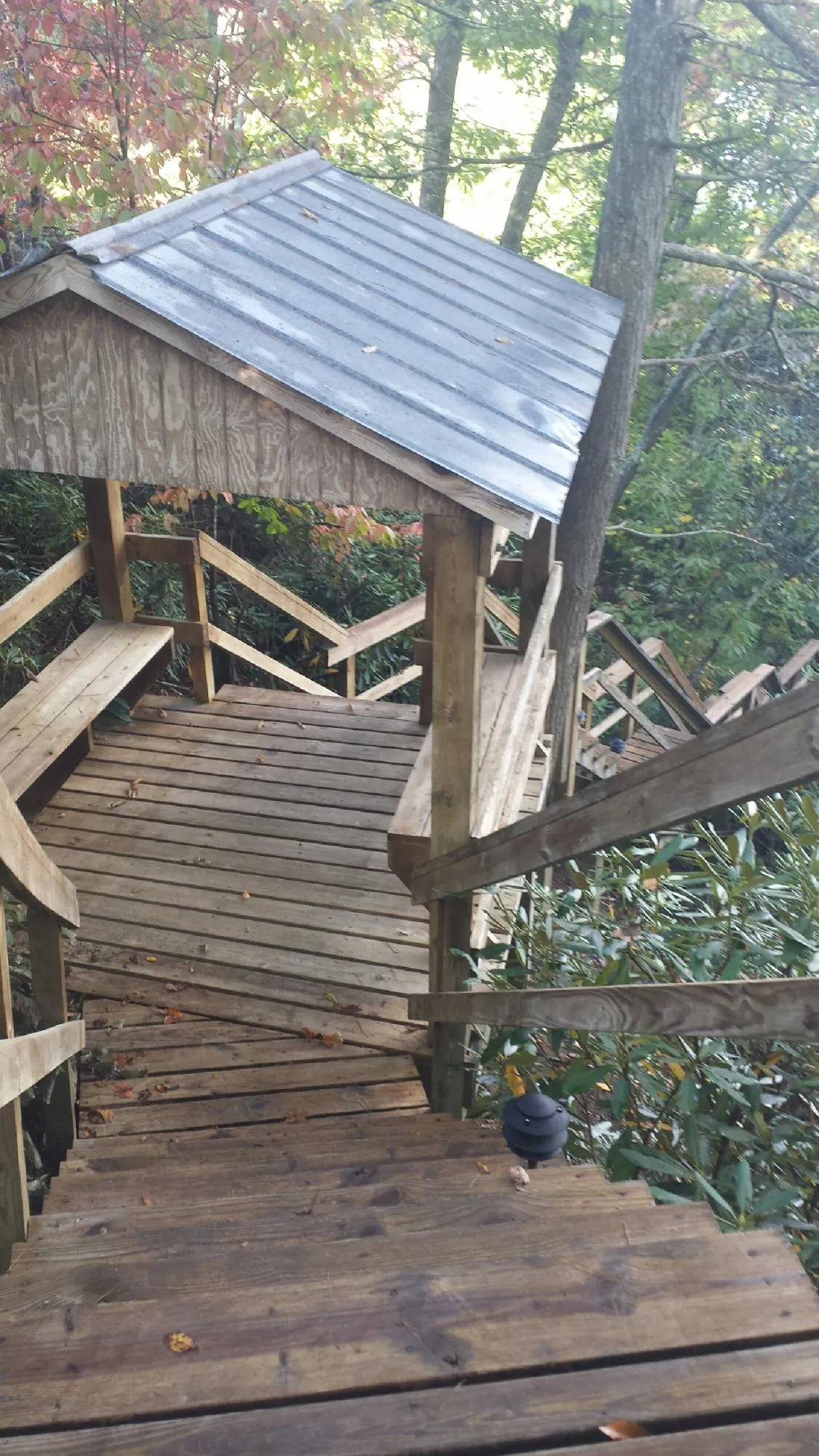 Metal roofed shelter over wooden steps on a wooded walkway — Skylight Repair & Installation work by our crew in Indio